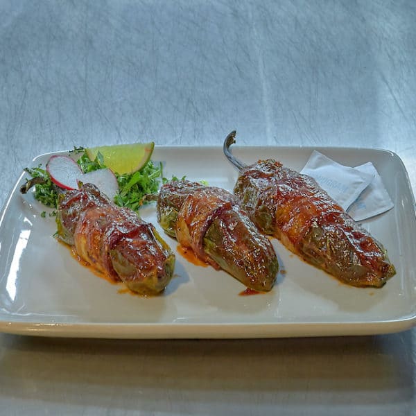 roasted jalapenos wrapped in bacon stuffed with cheese and drizzled in sauce from fort worth texas kitchen