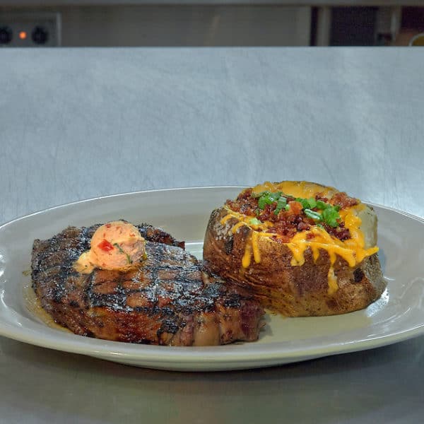 chargrilled steak served with herbed butter and a loaded baked potato fort worth texas kitchen